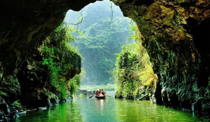Rowing boat entering a limestone cave in Tam Coc, Ninh Binh Vietnam
